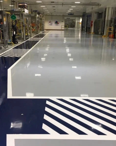 Piso industrial com revestimento epóxi autonivelante — superfície contínua sem emendas em ambiente de produção